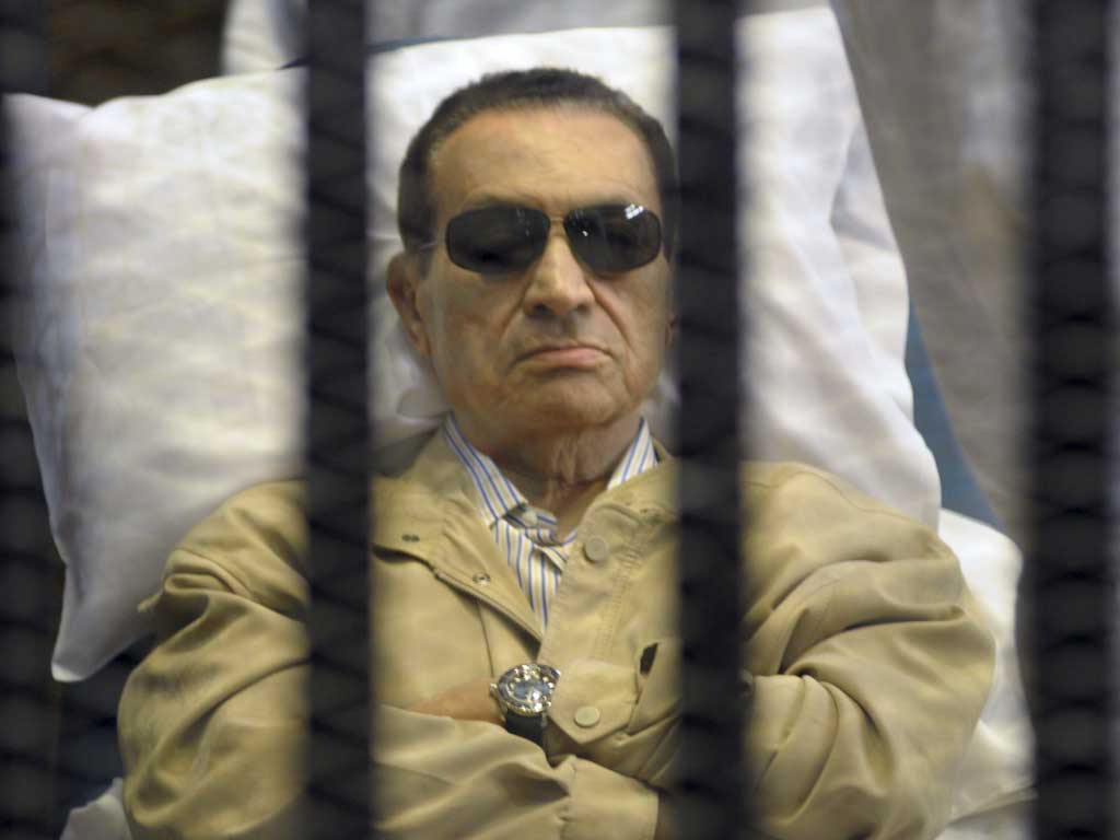 Former Egyptian President Hosni Mubarak lays on a gurney inside a barred cage in the police academy courthouse in Cairo