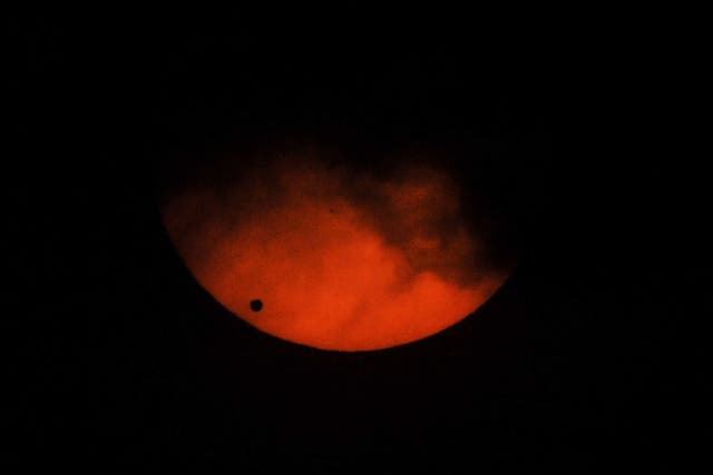 Venus (L) viewed as a small black dot, passes across the sun as seen from a weather observatory in Manila on June 6, 2012. Sky-gazers around the world held up their telescopes and viewing glasses June 6, to watch Venus slide across the sun -- a rare celestial phenomenon that will not happen again for more than 100 years. Other small dots on the right of the photo are called sun spots.
