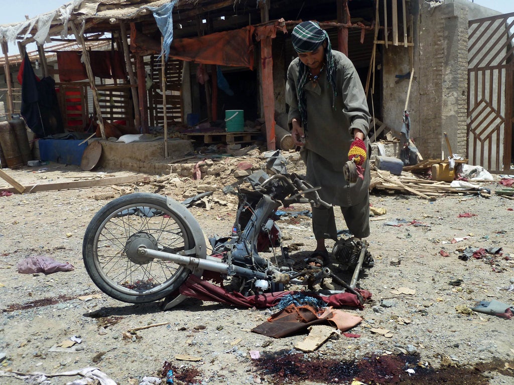 An Afghan man inspects a motorcycle used in the suicide attack in a parking lot holding dozens of trucks supplying the NATO-run Kandahar Air Base