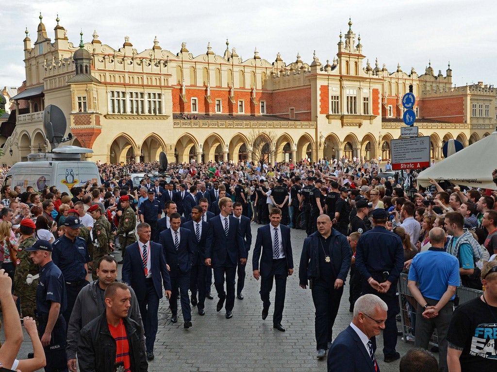 The England squad walk past crowds of fans in front of the Sukiennice in Krakow yesterday