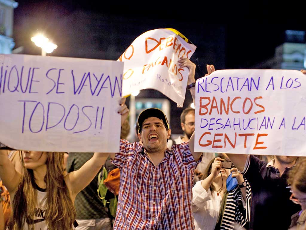 Demonstrators in Madrid hold up placards saying: ‘Everybody out’; ‘We don’t owe, we don’t pay’; and ‘They rescue the banks and evict people'