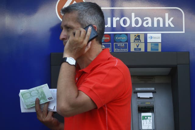 A Greek man holds 100 Euro bills which he just withdrew from a branch of Eurobank in central Athens 