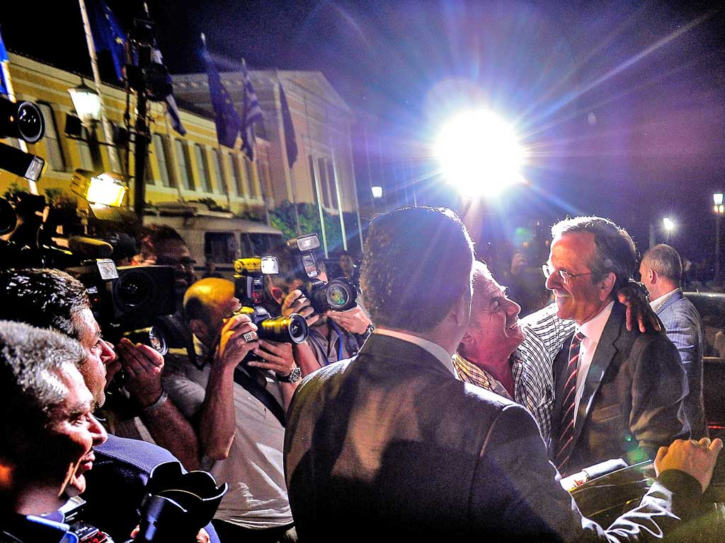 The victorious New Democracy leader Antonis Samaras, right, is congratulated by a supporter in Athens last night