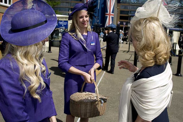 Two dress code assistants chat with a racegoer before she enters the grandstand