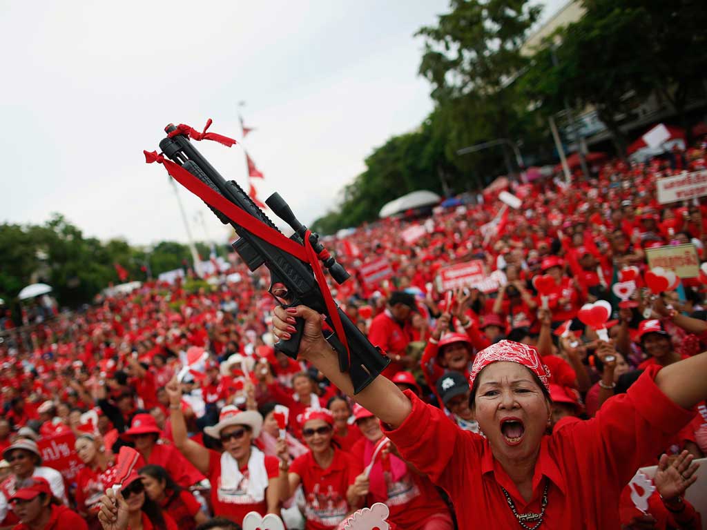 A member of the "red shirt" movement holds a toy gun as thousands gather at the Democracy Monument in Bangkok