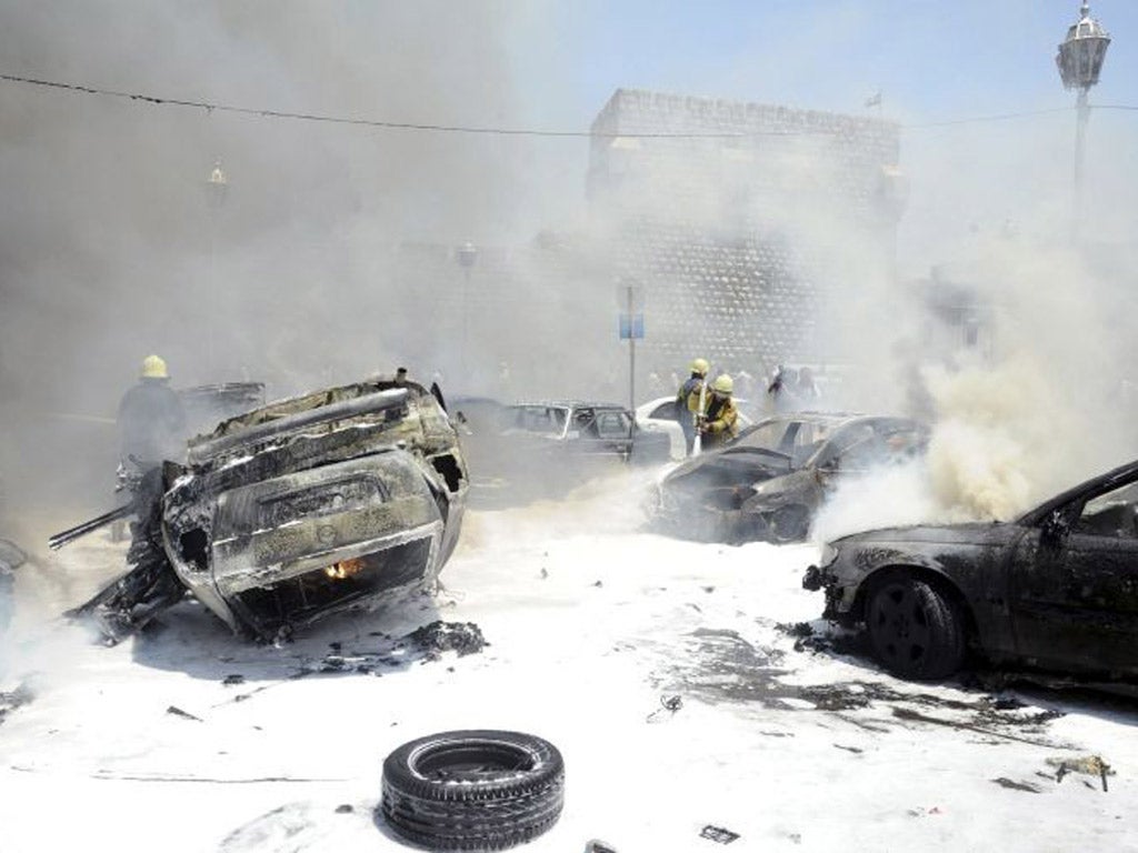 Civil Defence members extinguish fires on cars at the site of an explosion outside Syria's highest court in central Damascus