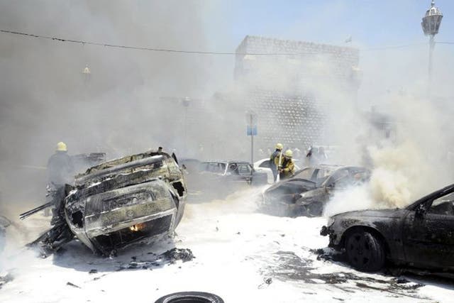 Civil Defence members extinguish fires on cars at the site of an explosion outside Syria's highest court in central Damascus