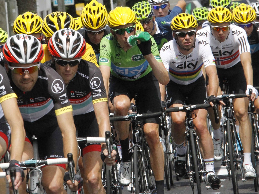 Bradley Wiggins (centre) has a drink on a hard day while Mark Cavendish (third from right) keeps close