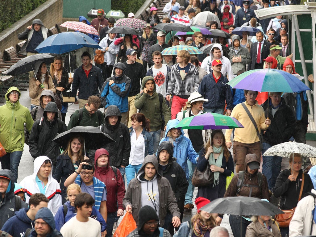 Spectators shield themselves from the rain at Wimbledon