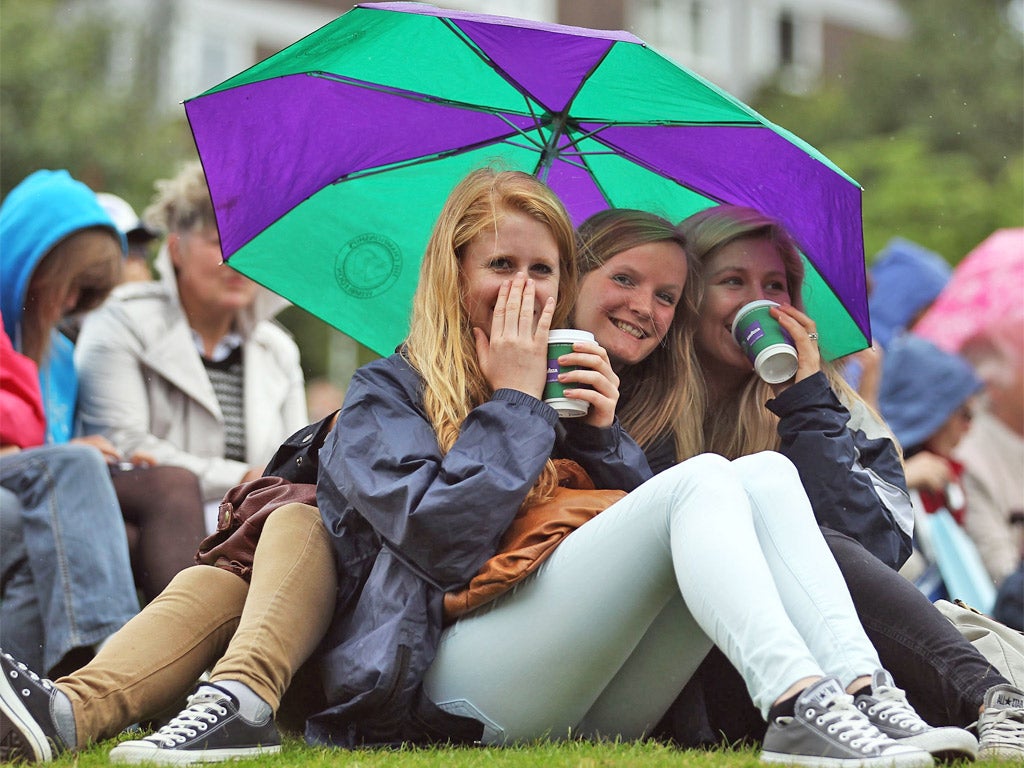 Spectators huddle under an umbrella as the rain came down on SW19 yesterday