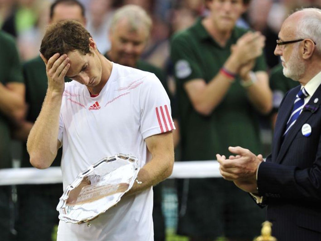 Murray collects his runner's-up trophy with a grimace, while Federer celebrates his seventh Wimbledon title