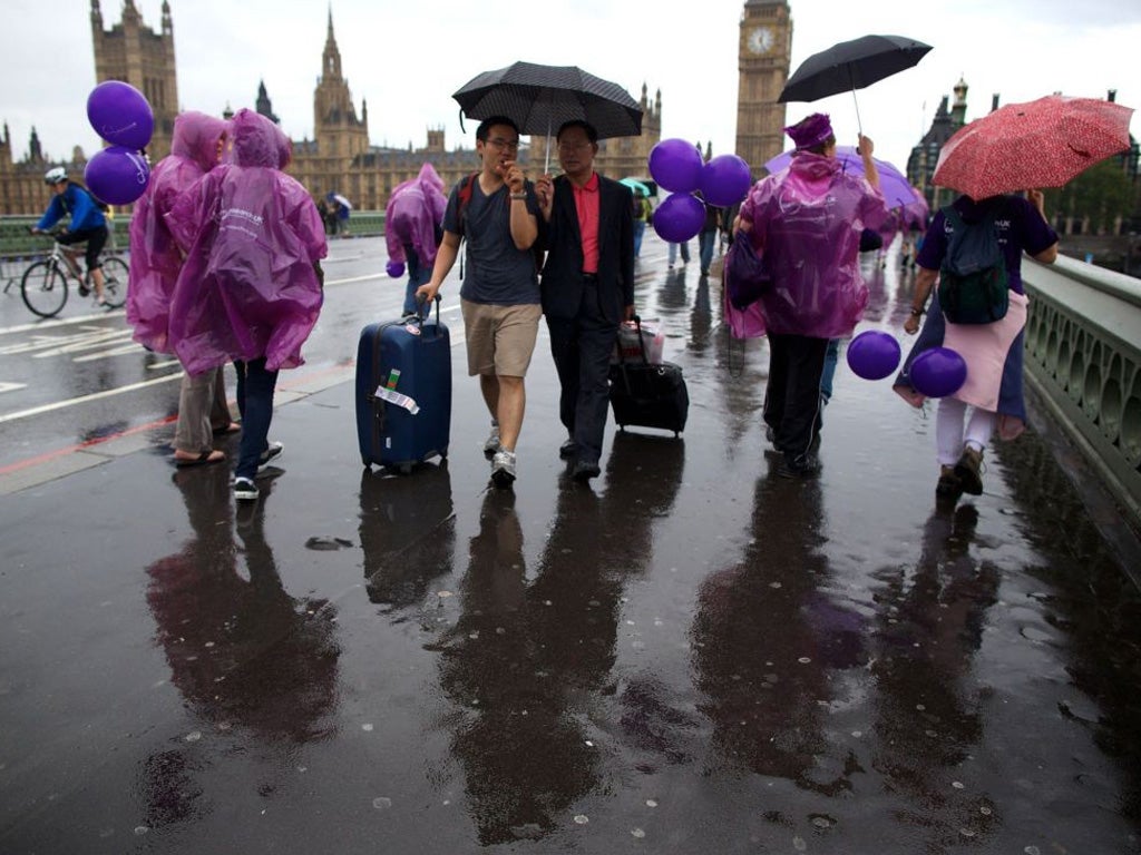Walkers cross a rain-lashed Westminster Bridge yesterday