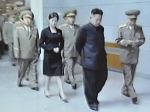 North Korean TV shows an unidentified woman close behind Kim Jong-un