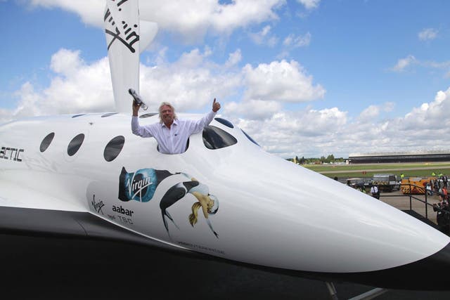 British billionaire Richard Branson poses for the photographers in the window of a replica of the Virgin Galactic