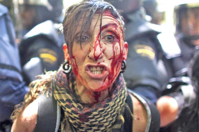 An injured protester is detained by riot police