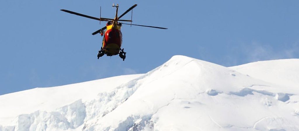 A rescue helicopter patrols above the avalanche site on Mont Maudit