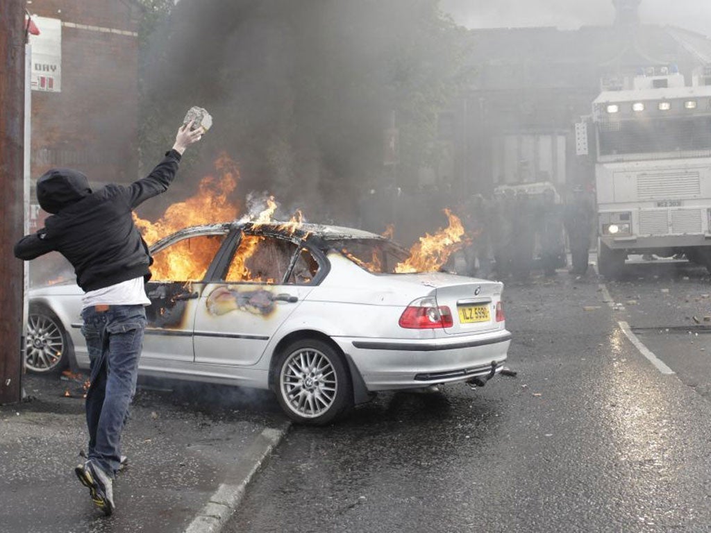 A protestor throws a rock at police lines in Belfast yesterday