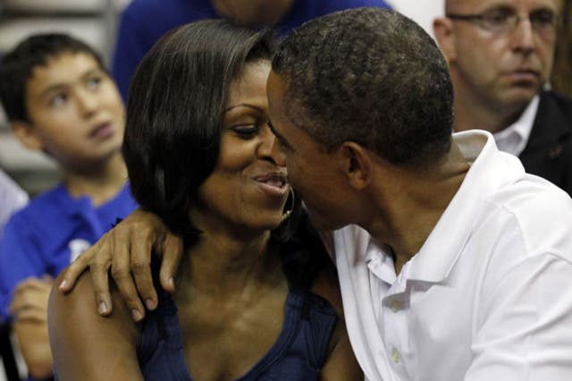 Barack Obama leans in to kiss first lady Michelle at the game