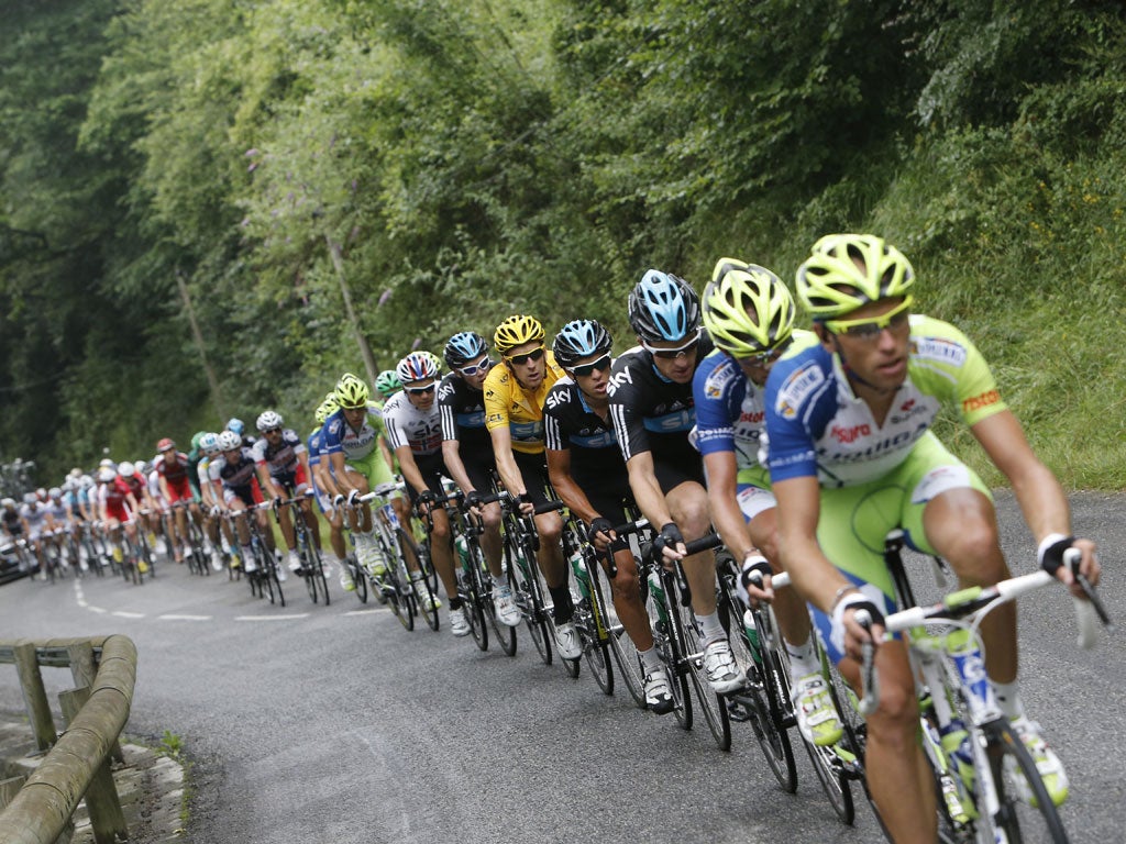 Bradley Wiggins (in yellow) keeps an eye on the pack as they climb Col des Ares yesterday