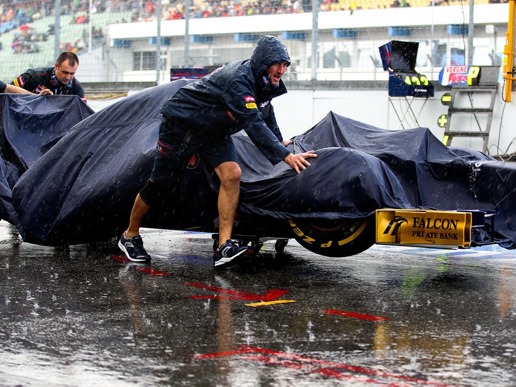 Wet, wet, wet: Technicians push a Torro Rosso through the pitlane in the middle of a heavy downpour during yesterday's qualifying for the German Grand Prix