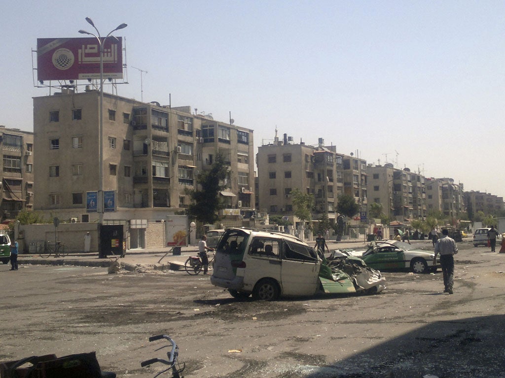South Damascus yesterday: Syrians walk past vehicles wrecked by fighting between rebels and government forces