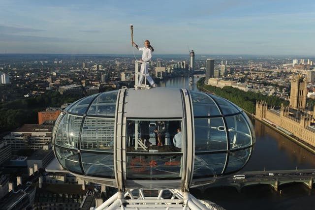 Amelia Hempleman-Adams poses with the Olympic Flame on top of a London Eye pod