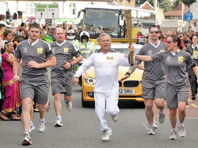 Sir Martin Sorrell carries the Olympic flame through the streets of
Redbridge in London yesterday