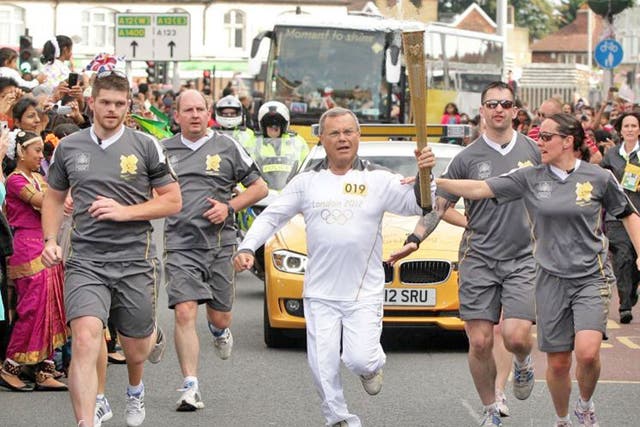 Sir Martin Sorrell carries the Olympic flame through the streets of
Redbridge in London yesterday