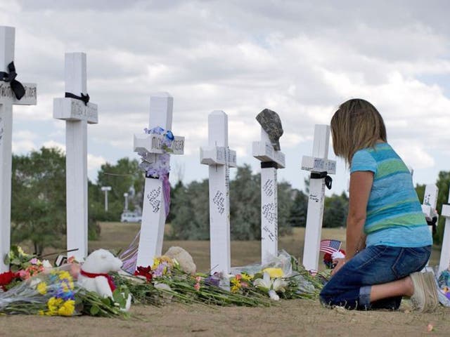 A woman kneels at the crosses at a memorial near the Century 16 movie theater in Aurora, Colorado