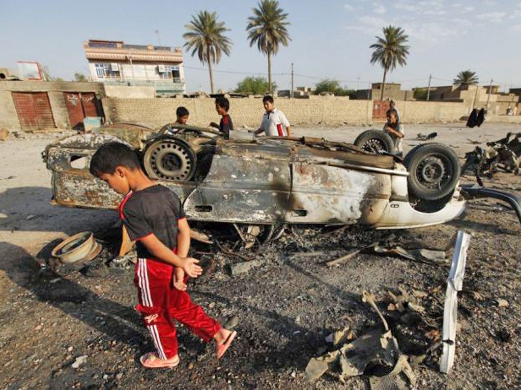 Iraqi boys inspect a bombed car in Mahmudiya, south of Baghdad, where three car bombs claimed 11 lives