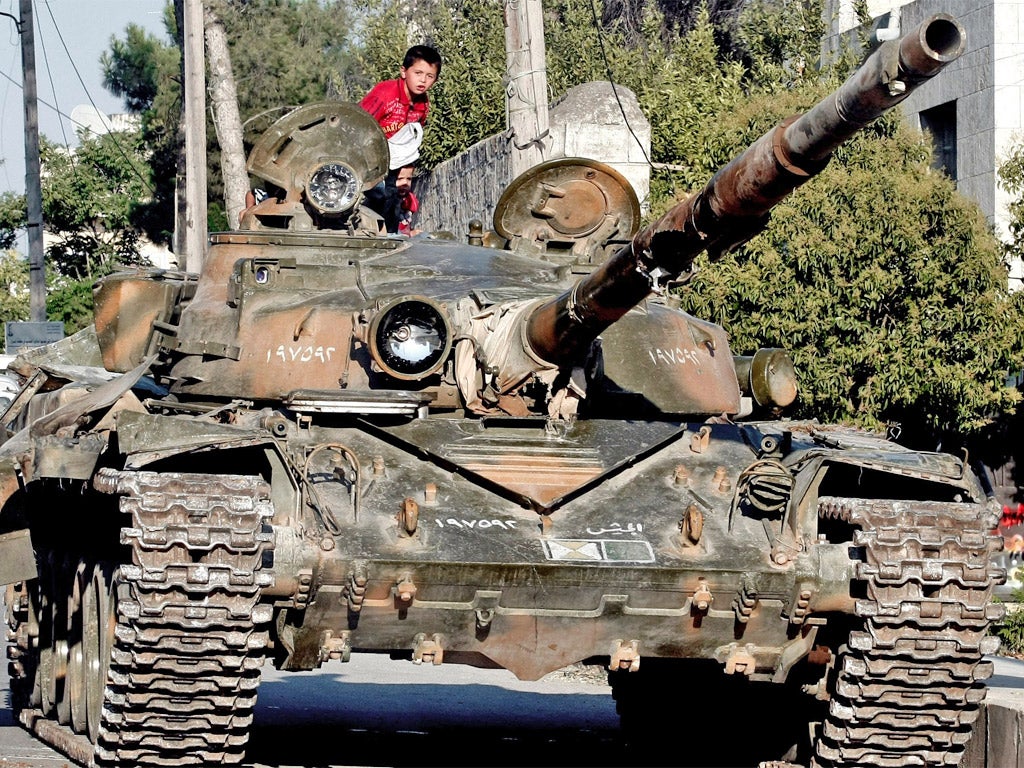 A Syrian boy sits atop a damaged military tank at the border town of Azaz, 20 miles north of Aleppo