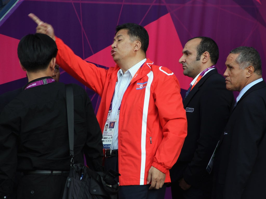 An official of DPR Korea gestures to the national flag as it is displayed wrongly