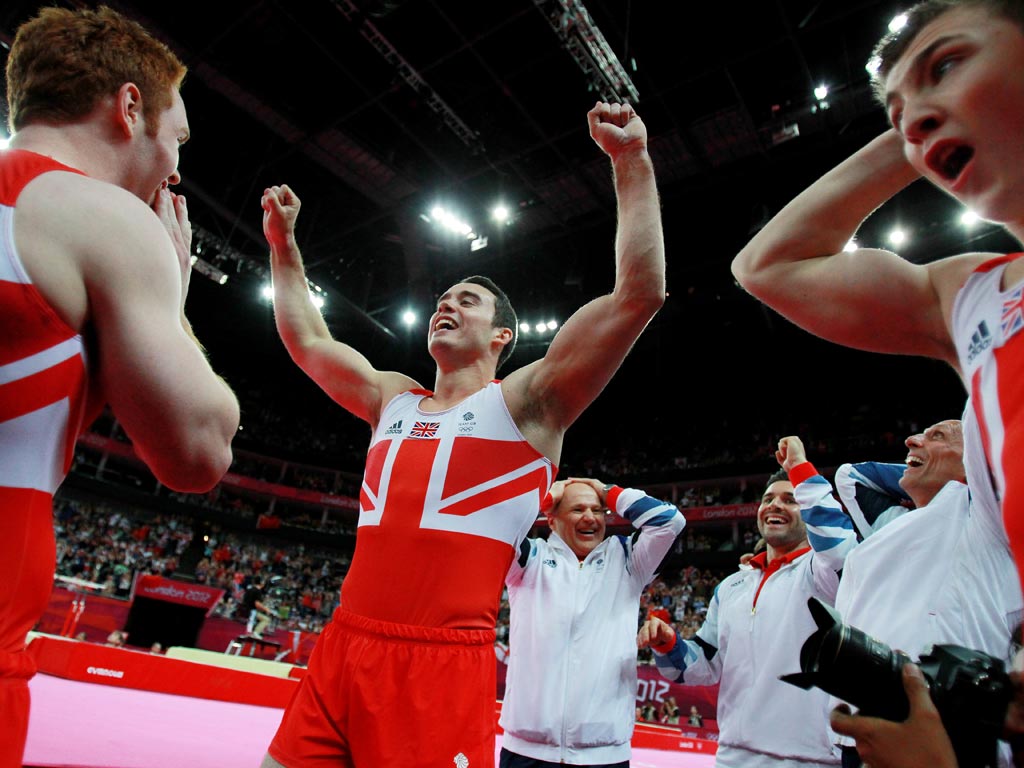 Daniel Purvis, Kristian Thomas and Sam Oldham of Great Britain react after hearing the scores on the final rotation in the Artistic Gymnastics Men's Team final