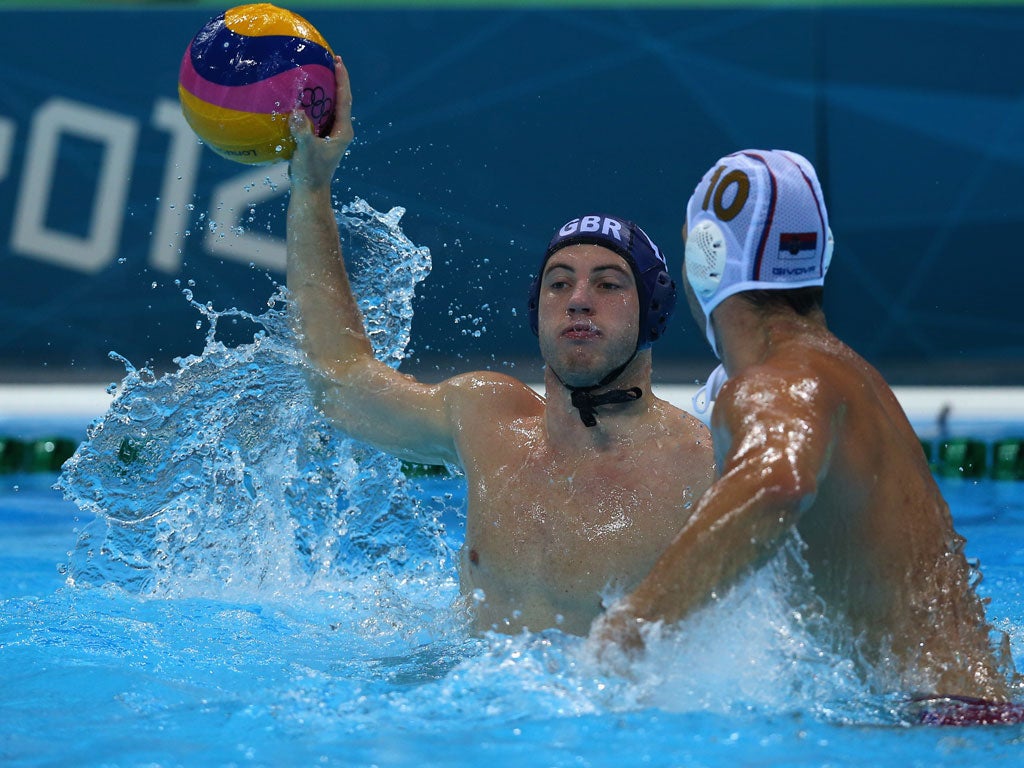 Sean King of Great Britain passes under pressure from Filip Filipovic of Serbia during the Men's Water Polo