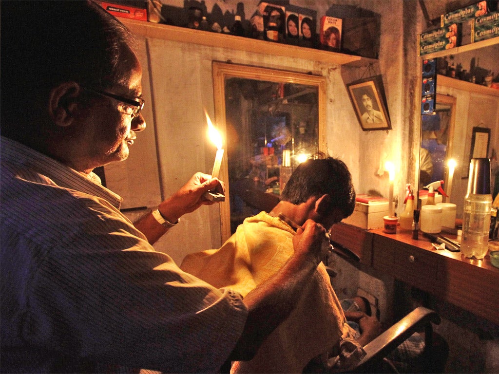 A barber in Kolkata plies his trade by candlelight; the northern city was one of many hit by the blackout