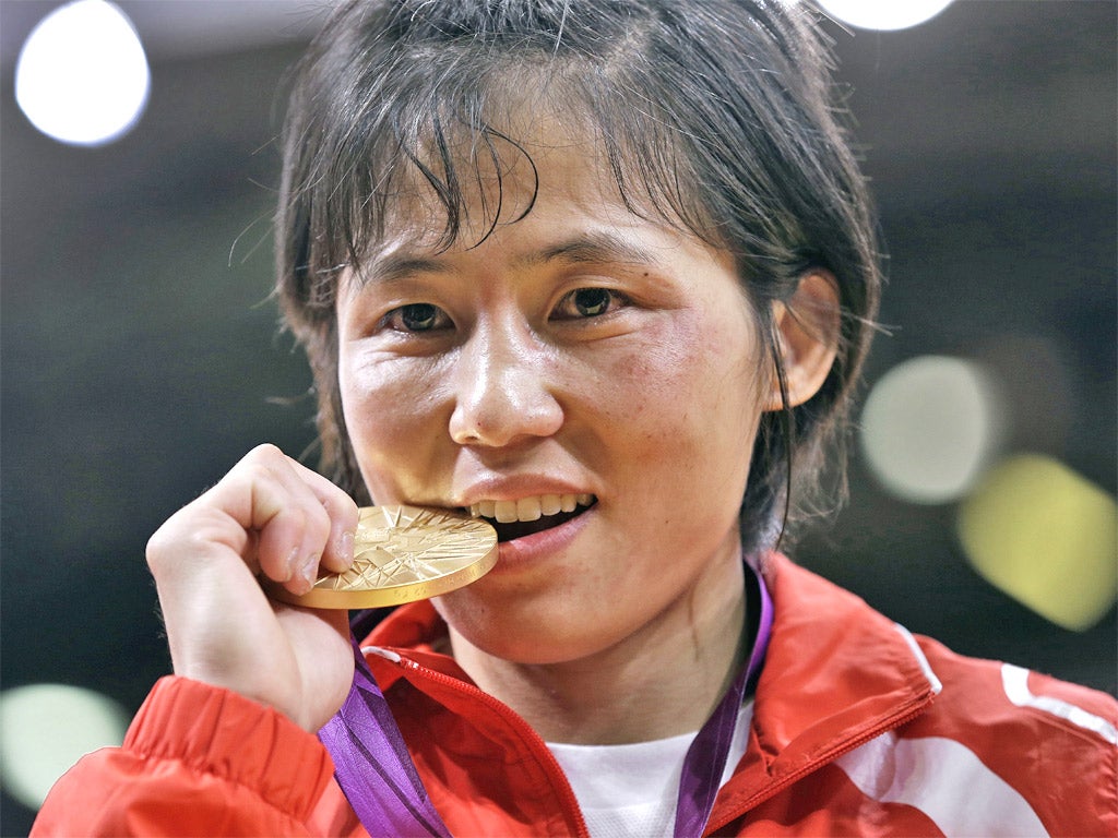 An Kum-Ae has a nibble on the gold medal that she won on the Judo floor