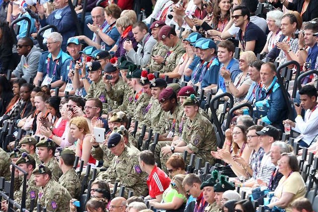 Soldiers sat with spectators watch as Great Britain's Jessica Ennis competes in heat 5 of the 100metre hurdles in the first event of the Heptathlon 