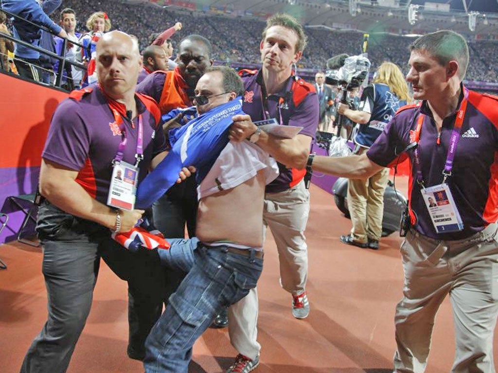 A spectator is led away by security staff after a bottle landed on the
track