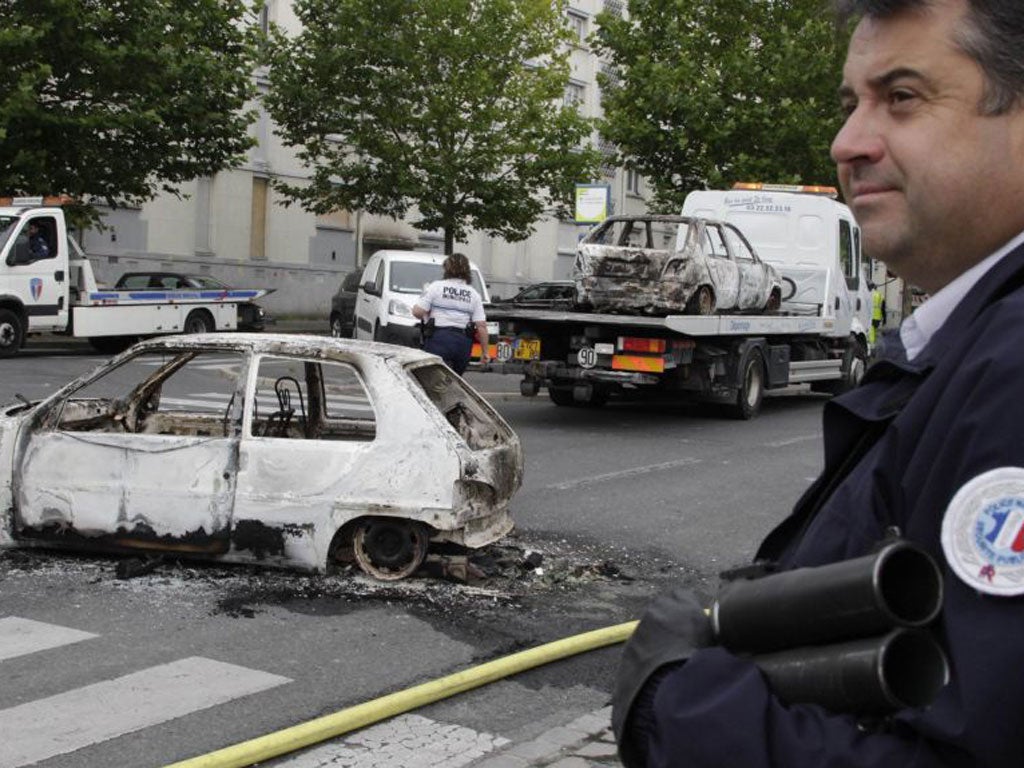 French police stand guard near cars destroyed in overnight clashes in Amiens