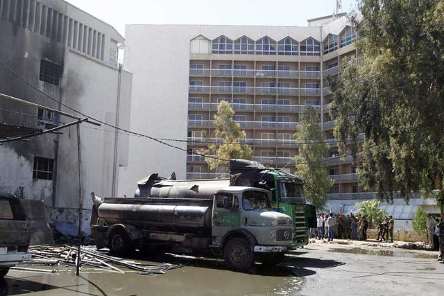 Burnt vehicles are seen after a bomb exploded at a military site near a hotel used by United Nations monitors in Damascus