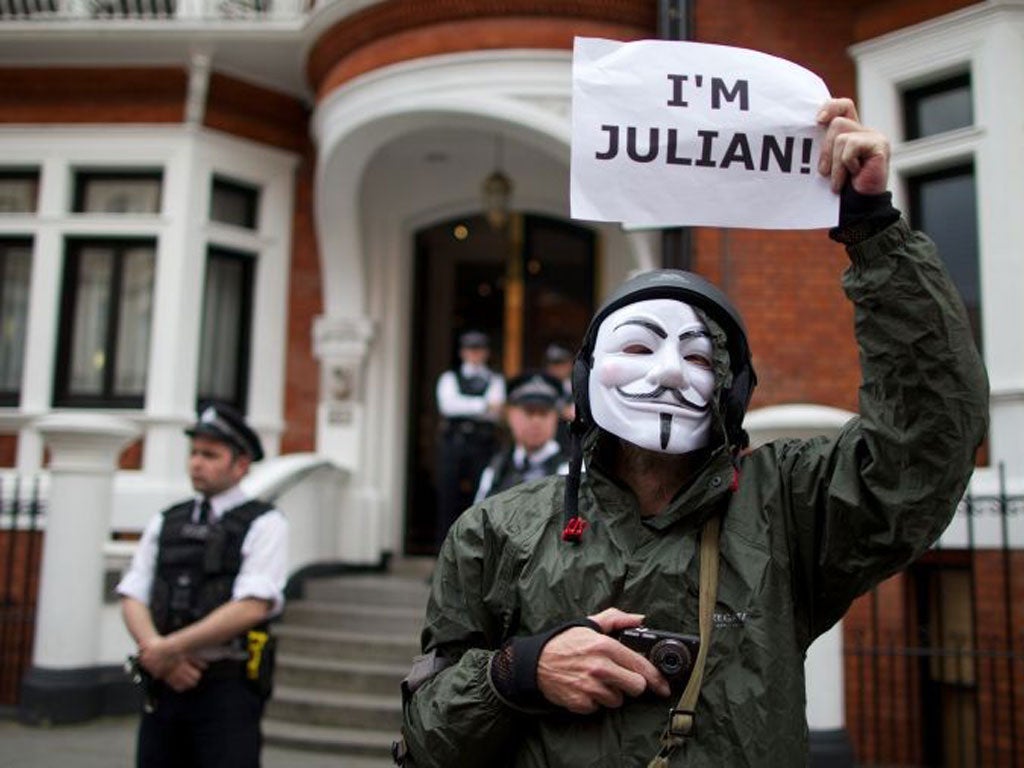 A member of Anonymous in a Guy Fawkes mask outside the embassy