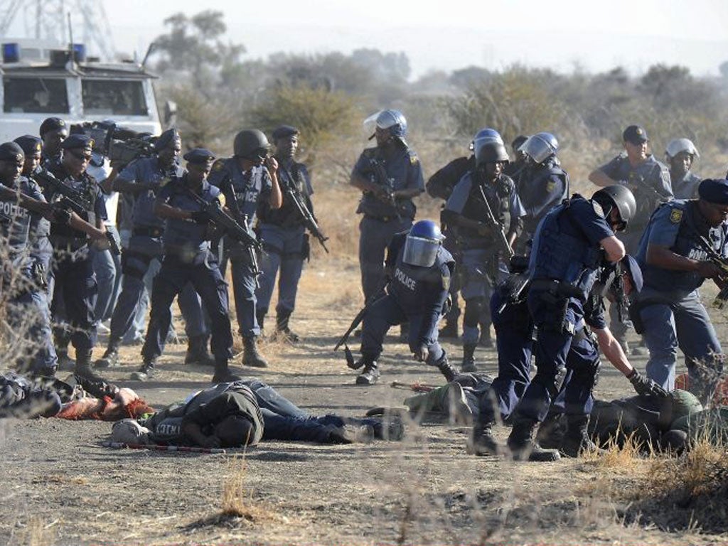 Police check the bodies of miners after opening fire on the strikers outside the Nkageng settlement last August