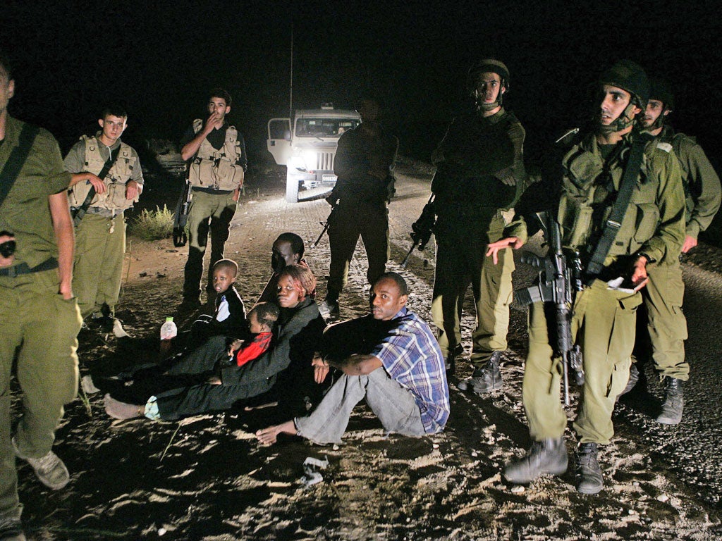 Sudanese refugees sit on the ground surrounded by Israeli soldiers after crossing illegally from Egypt into Israel