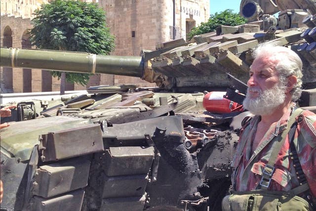 Private Abul Fidar of the Syrian army stands beside a damaged T-72 tank below the Aleppo Citadel