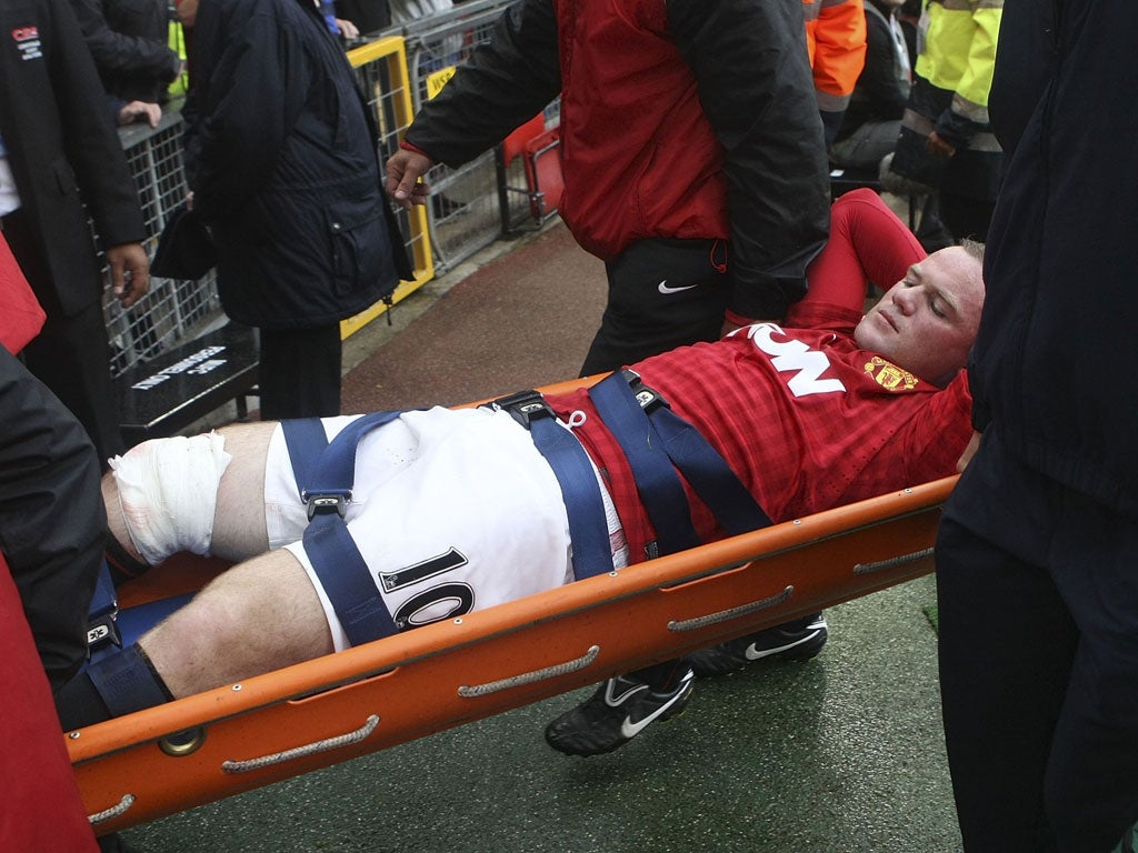 Pain game: Manchester United's Wayne Rooney is stretchered off with a leg injury sustained in a clash with Fulham's Hugo Rodallega during the Premier League clash at Old Trafford yesterday