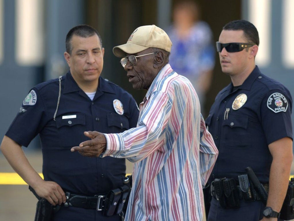 Preston Carter, 100, talks with police officers after his car went onto a sidewalk and plowed into a group of parents and children outside a South Los Angeles elementary school