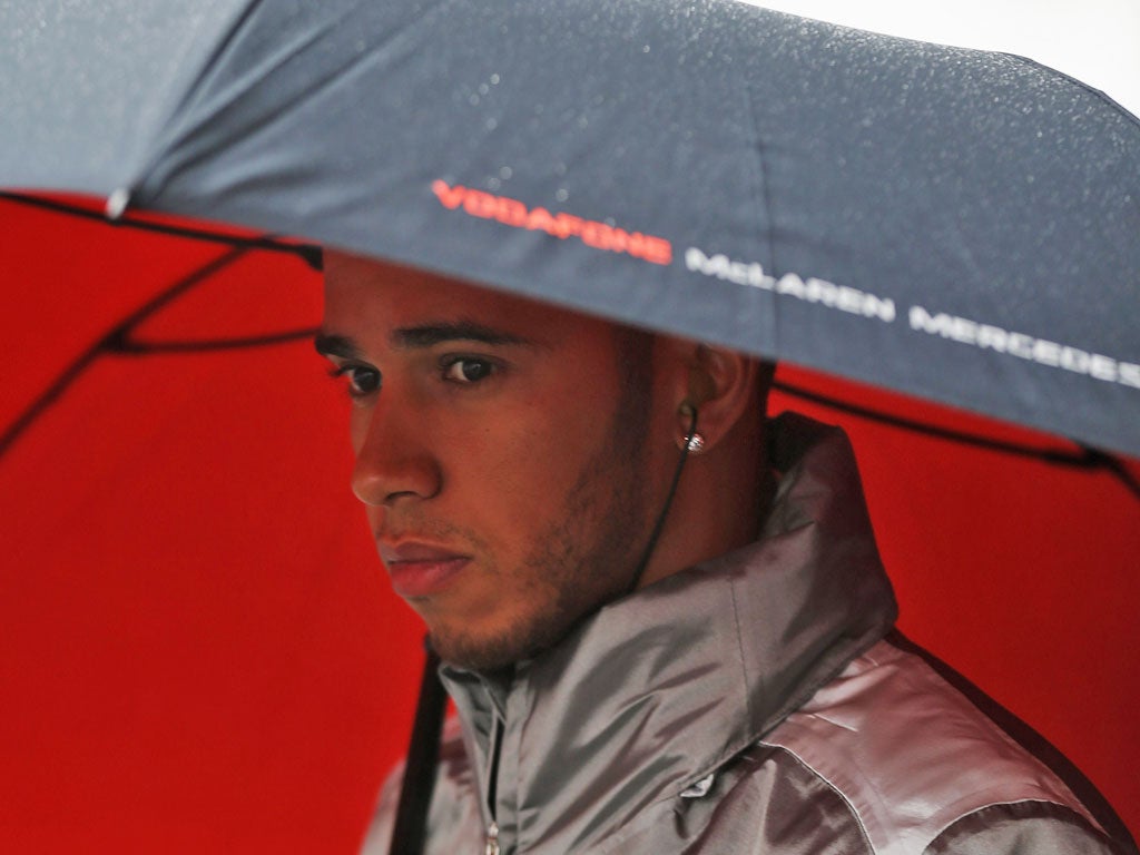Lewis Hamilton strolls along a wet and windy pitlane yesterday
