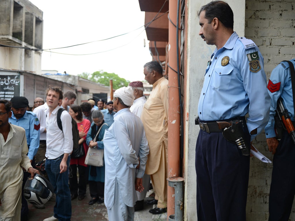 Pakistani policemen keep watch as minority Christians and journalists gather outside the court building during the case hearing