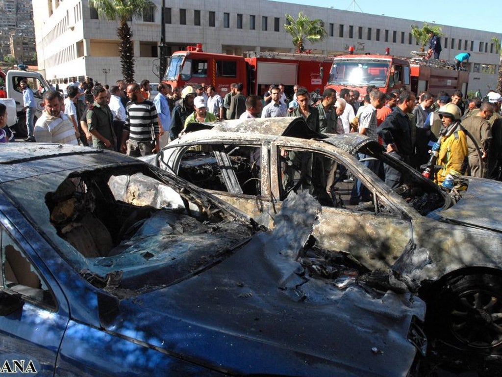 Syrian policemen inspect the scene where a booby-trapped car exploded in front of Syrian Information Ministry and Justice Palace at the Mazzah highway in Damascus