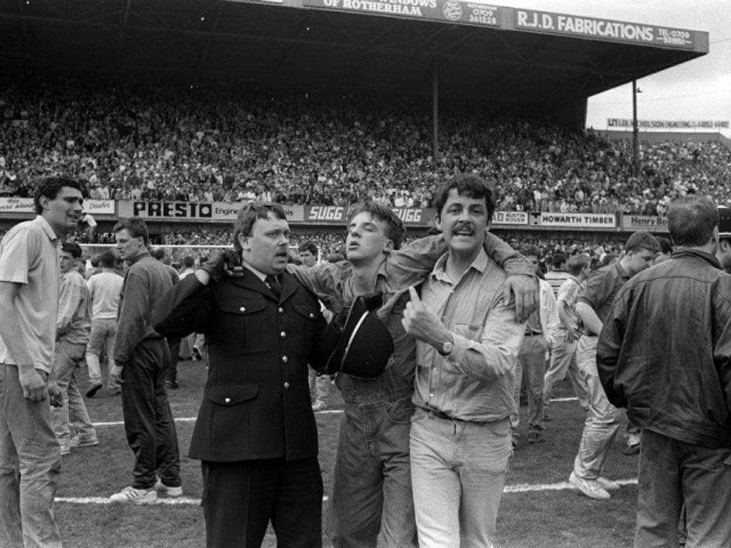 An injured fan is helped off the pitch at Hillsborough